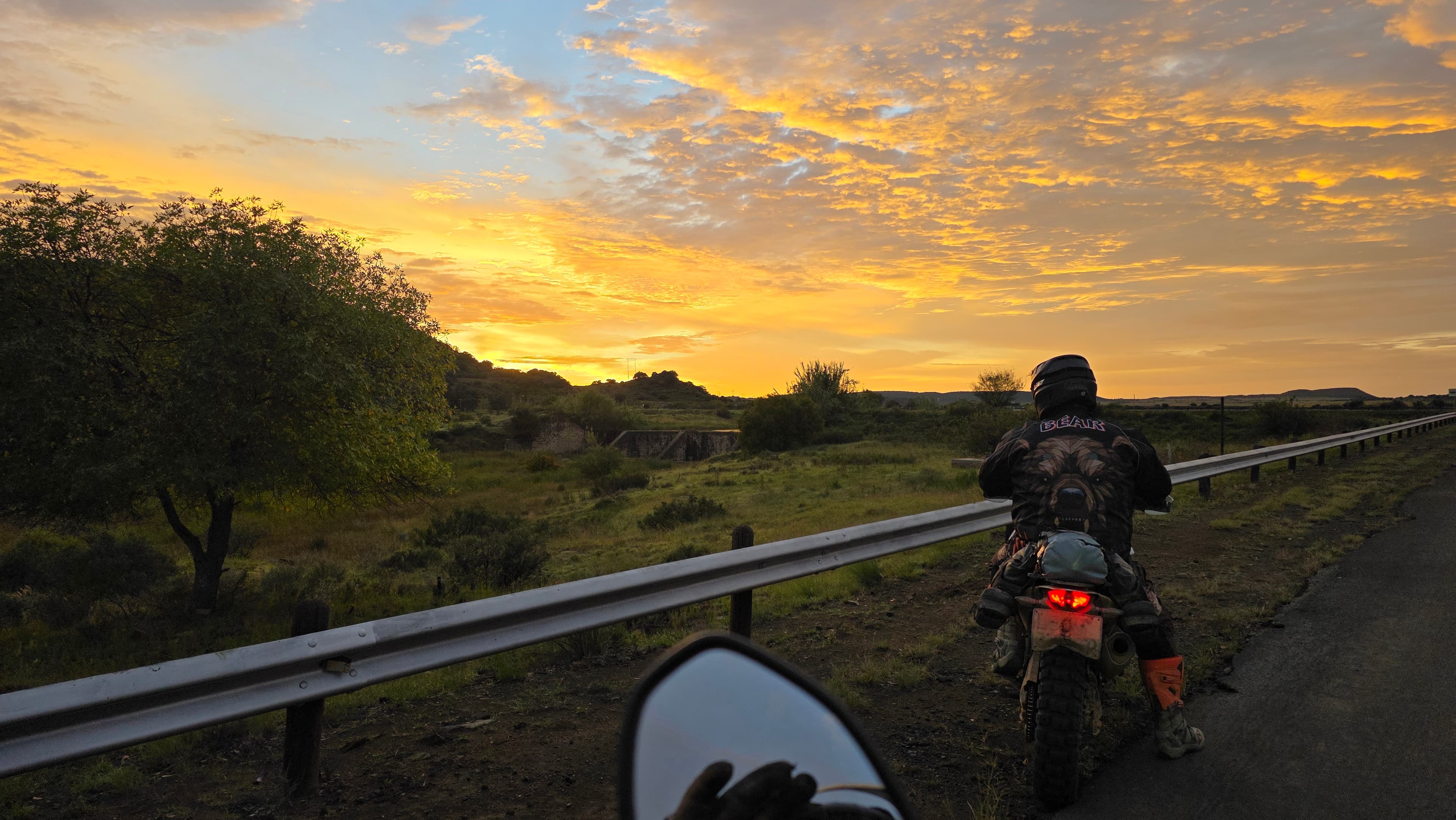 WillTour rider pausing roadside at sunrise, golden sky over the Karoo landscape during The Southern Arc ride.